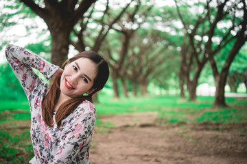 Portrait of Beautiful thai woman smile,sit on lawn use hand touch head under tunnel tree,sweet tone,pastel tone,vintage,film