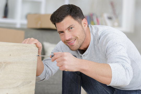 Man Assembling Furniture At Home On The Floor