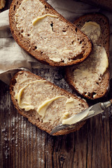 Slices of rustic sourdough bread with homemade butter on wooden table, top view
