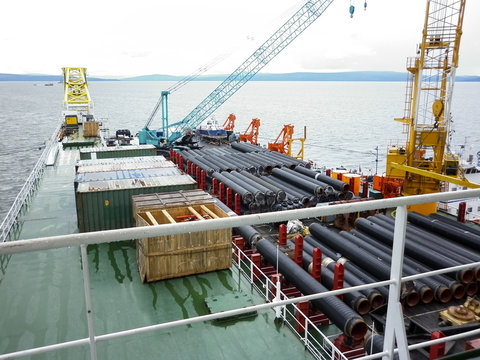 The deck lay barge. Pipes and Lifting cranes on the ship. Equipment for laying a pipeline on the seabed