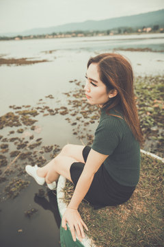 Beautiful thai woman very sad from unrequited love,rethink,think over,vintage style,dark tone,broken heart,asian girl,Sitting on a pier beside the dam