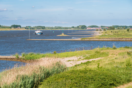 Ship sailing upstream along groynes on Waal river, Netherlands