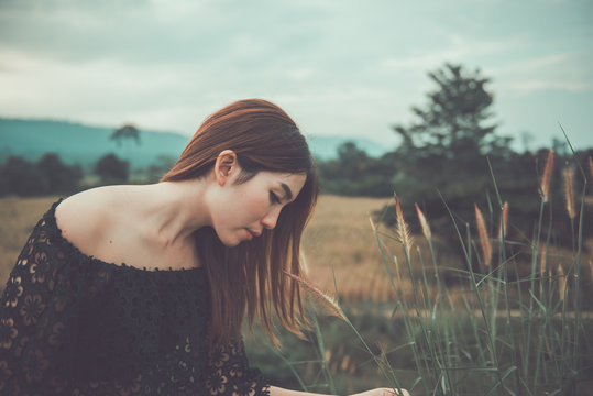 Beautiful thai woman use hand touch flower grass,very sad from unrequited love,rethink,think over,vintage style,dark tone,broken heart,asian girl