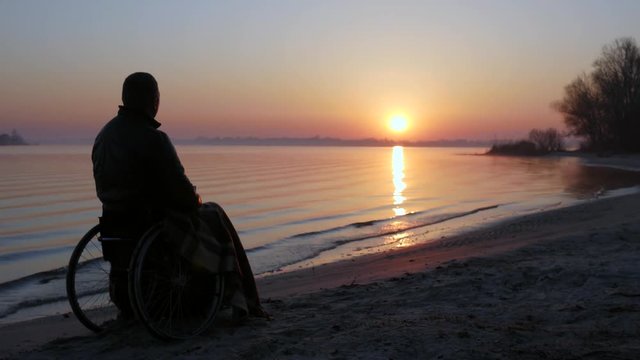expectation, invalid on wheelchair, cup of warming drink in hands of crippled Man, disabled person, handicapped male meets dawn with hope, sad sick person near river in nature, rising sun, sunse