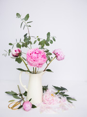Pink peonies in white jug on white canvas background