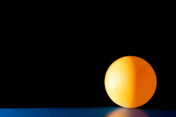 Yellow ball on a blue dark background illuminated by a side beam of light