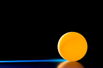 Yellow ball on a blue dark background illuminated by a side beam of light