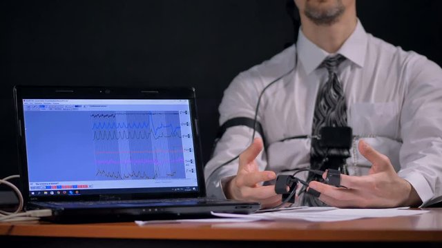 Polygraph laptop screen showing graphs as subject's hands shake.