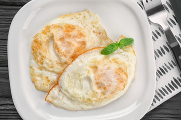 Delicious over hard eggs with basil leaves on plate