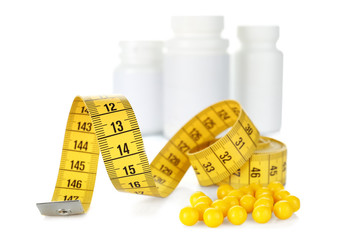 Weight loss supplements and measuring tape isolated on white