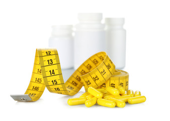 Weight loss supplements and measuring tape isolated on white