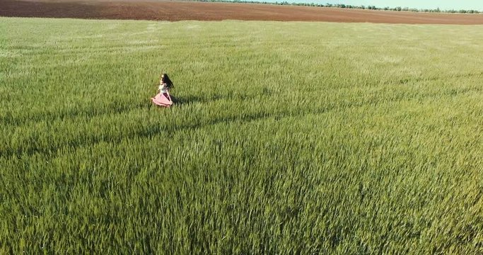 Young woman running through wheat field