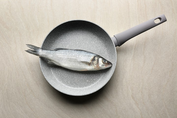 Frying pan with raw fish on table