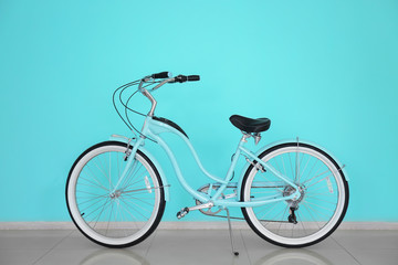 Modern two-wheeled bicycle indoors near color wall