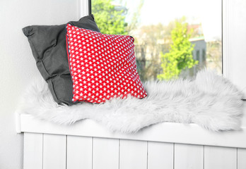 Two pillows and  plaid on a window sill
