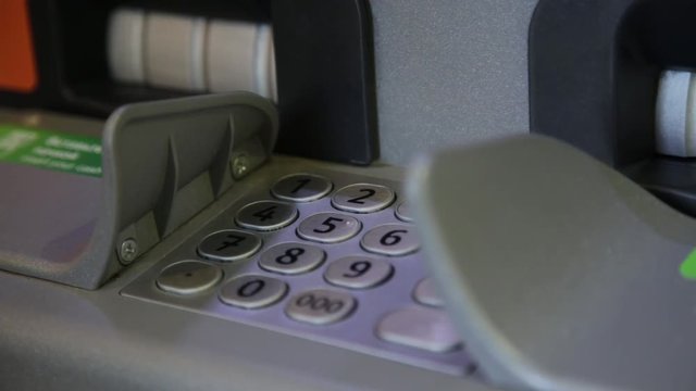man using banking cash machine - ATM. Man dials a pincode