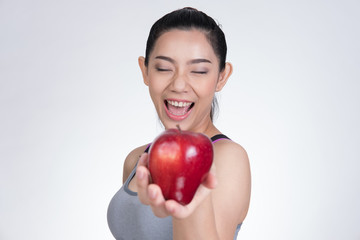 asian healthy athletic sporty girl with red apple after training. attractive smiling woman standing against white background.