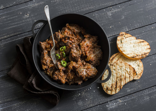 Easy peri-peri chicken livers in a cast iron skillet on a dark background, top view. Simple rustic lunch