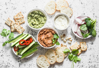 Vegetarian dip table. Eggplant, harissa, walnuts dip, broccoli dip, soft tofu and fresh vegetables on a light background, top view. Flat lay - obrazy, fototapety, plakaty