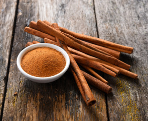 Cinnamon sticks and cinnamon powder on wood