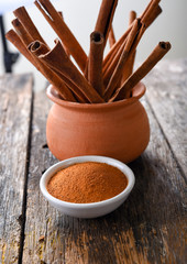 Cinnamon sticks and cinnamon powder on wood
