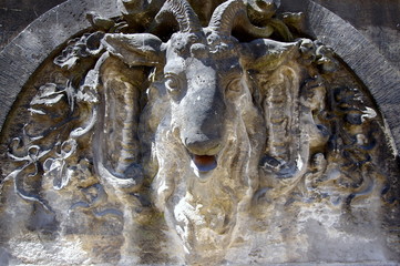 Płaskorzeźba przedstawiająca głowę uśmiechniętego kozła