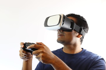 Young handsome gamer wearing virtual reality goggles and holding remote controller