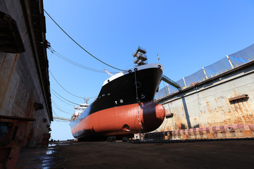 Oil tanker vessel black color on top and red color down below on dry dock to do repair