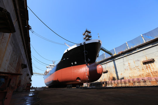 Oil tanker vessel black color on top and red color down below on dry dock to do repair