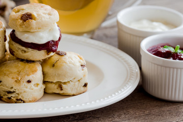 Homemade raisin scones serve with homemade strawberries jam,clotted cream and tea.Scones is English pastry for afternoon tea,cream tea.Delicious scones Devon shire or Cornish cream style.