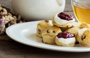 Homemade raisin scones serve with homemade strawberries jam,clotted cream and tea.Scones is English pastry for afternoon tea,cream tea.Delicious scones Devon shire or Cornish cream style.