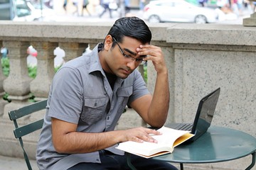 Man in deep thought concentrating while reading and doing work in a city urban location
