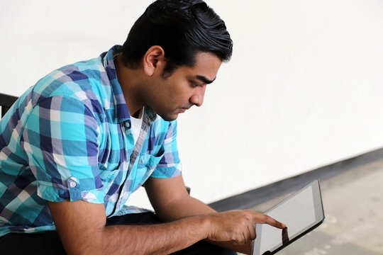 Young handsome man typing on display of tablet