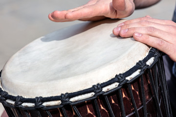 street talented musician playing african drum djembe outdoors. closeup of mans hands. 