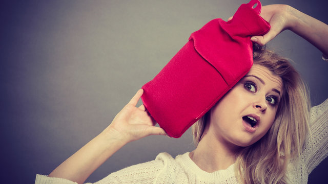 Woman holding red hot water bottle on head