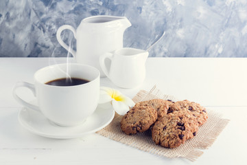 cup of coffee,milk,sugar,chocolate chip cookies  on white wooden background with loft wall style with light in concept relax time