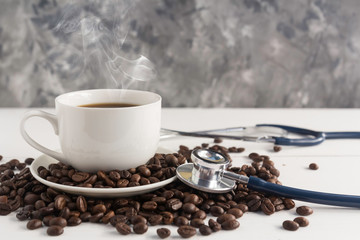 a cup of coffee ,coffee beans and stethoscope on white wooden background  in concept Health of coffee drinkers, quality of coffee