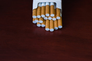 Pack of cigarettes on the table mahogany. Dark background