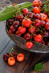 cherries on a dark wood background. selective focus on cherry in the bowl
