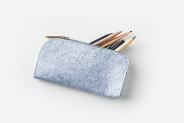 Top view of grey fabric pencil case with lot of pens on white background desk for mockup