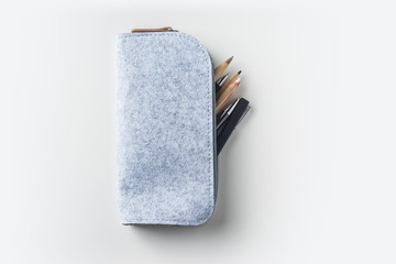 Top view of grey fabric pencil case with lot of pens on white background desk for mockup