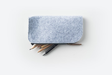 Top view of grey fabric pencil case with lot of pens on white background desk for mockup