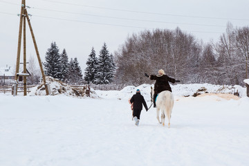 Girl, horse trainer and white horse on a winter