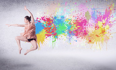 Obraz na płótnie Canvas Modern street dancer jumping with colorful paint splashes