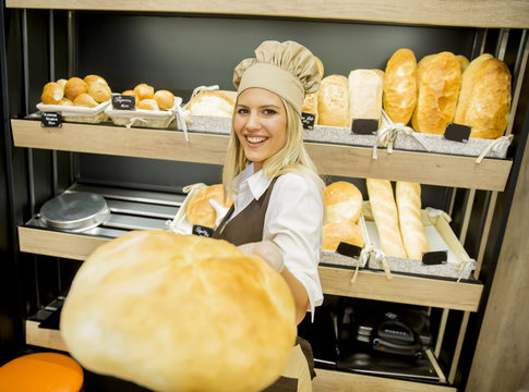 Pretty young woman selling bread in the bakery