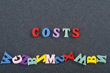 costs word on black board background composed from colorful abc alphabet block wooden letters, copy space for ad text. Learning english concept.