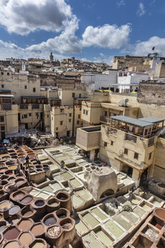 Traditional tannery with colorful basins in medina of Fes with town in background