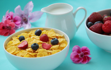 Breakfast. Corn flakes, milk and fresh fruits as blueberries and strawberries on blue background. Close up view.