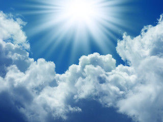Bright sun in the blue sky with cumulus clouds. Closeup
