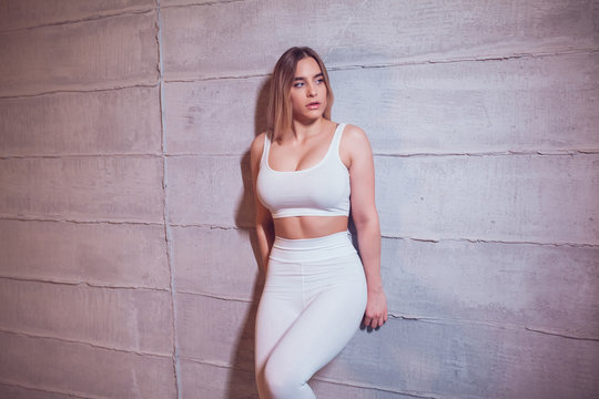 Sexy blonde woman with huge breast in a white top and leggings. Mock-up.